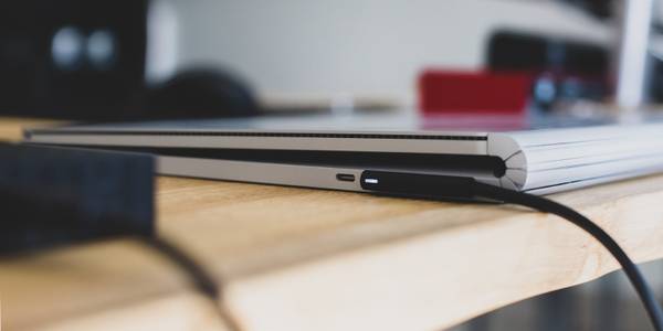 A sliver laptop on a table charging