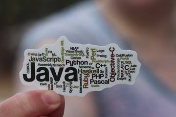 A person holding paper with Java text on it