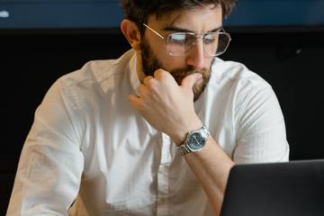 man uses laptop with thoughtful expression