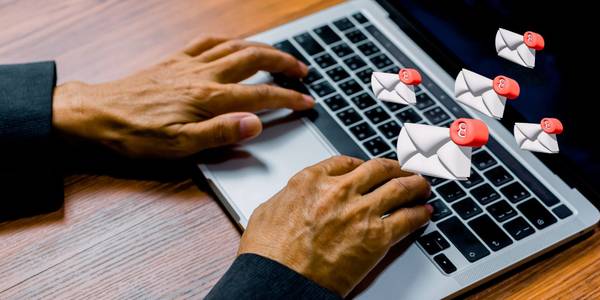 Man typing on laptop with email symbols