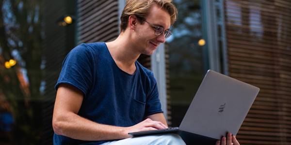 man wearing glasses and blue shirt using a macbook