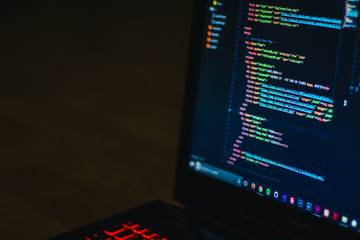 A laptop displaying markup in a text editor using a dark theme with bright primary colors.