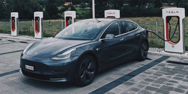 tesla car in parking lot connected to a charging dock