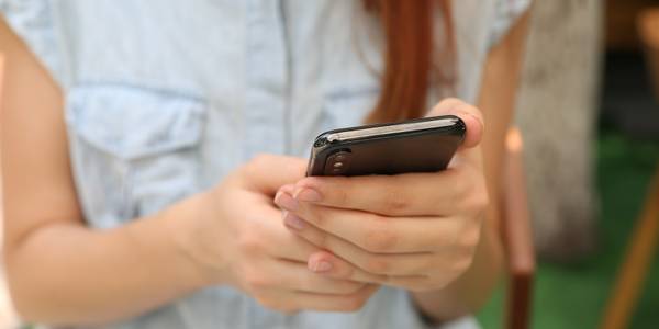 woman holding and using black smartphone