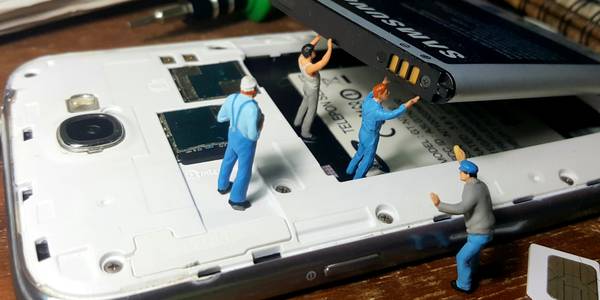 miniature people removing broken smartphone battery from its case