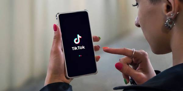 Women holding phone with TikTok logo on the screen