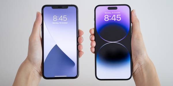 A person holding two iPhones showing their Lock Screens