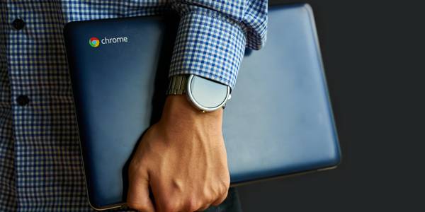 A close-up of a Chromebook being carried with one arm.