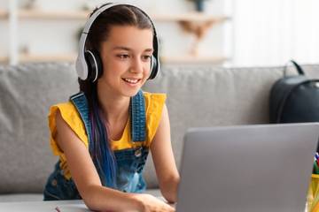 Girl playing on laptop wearing headphones
