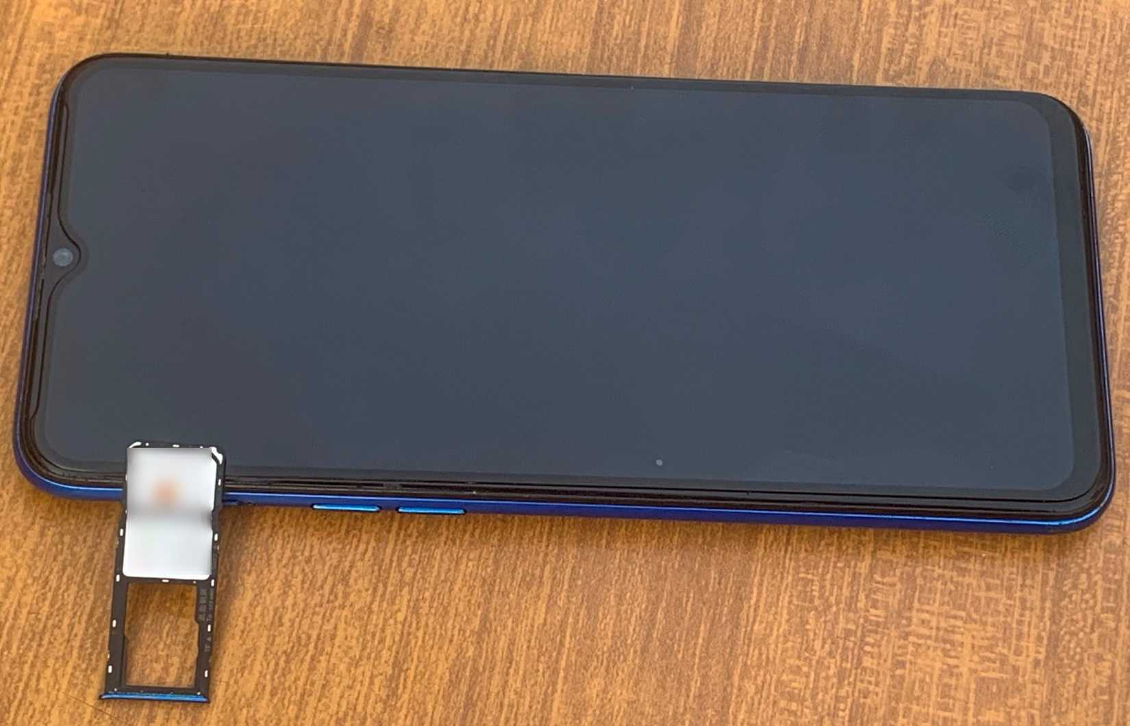 Android phone placed on a table with sim and memory card slots removed out of it.