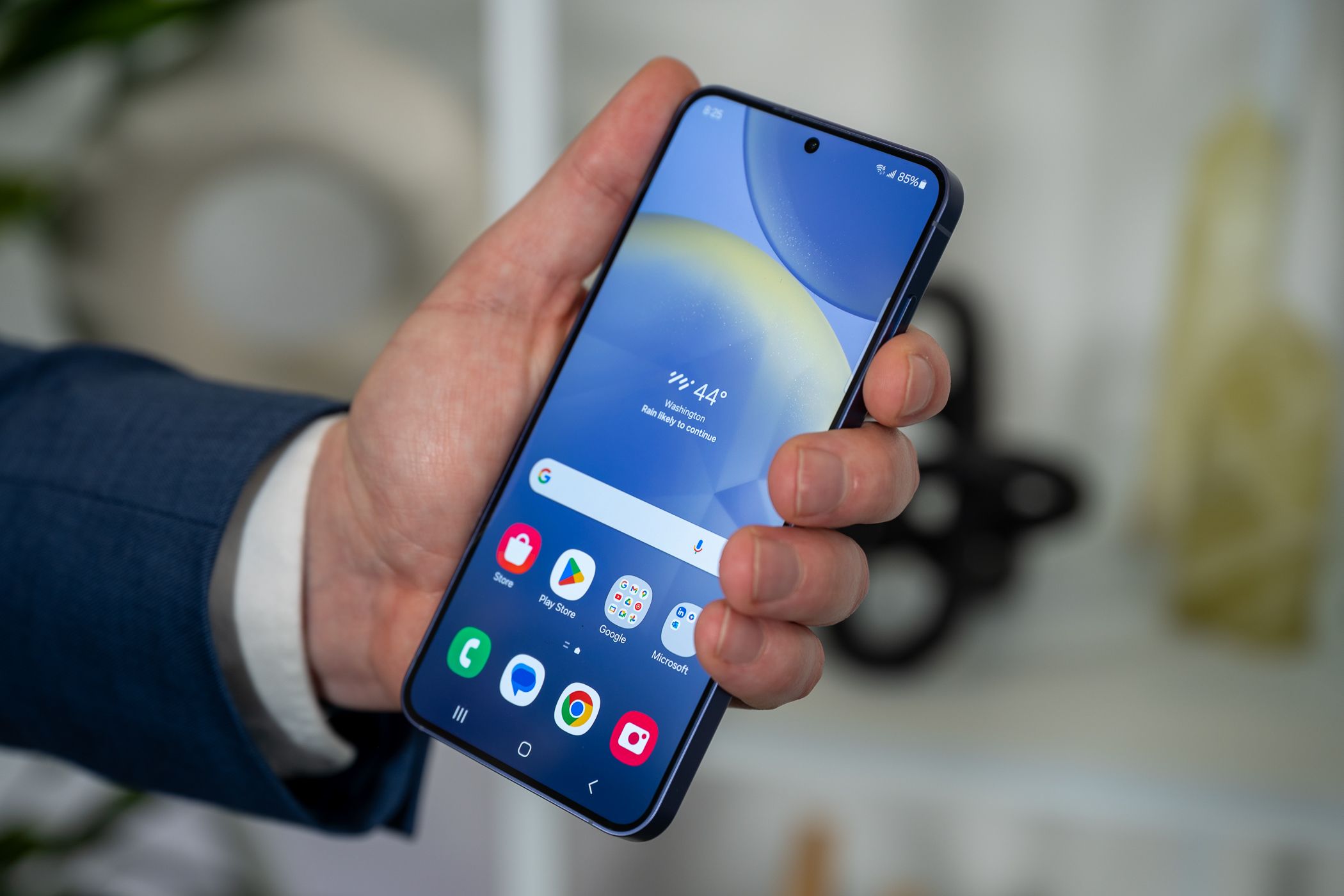 Person holding the Samsung Galaxy S24 showing its home screen