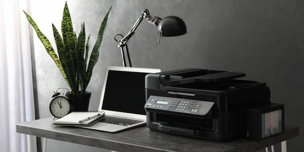 New all-in-one printer and laptop on grey table in office