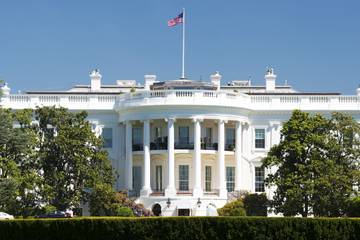 The White House, a wide white building with tall windows, columns, and a US flag.