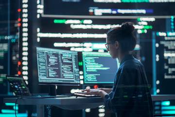 woman using two pc monitor for programming