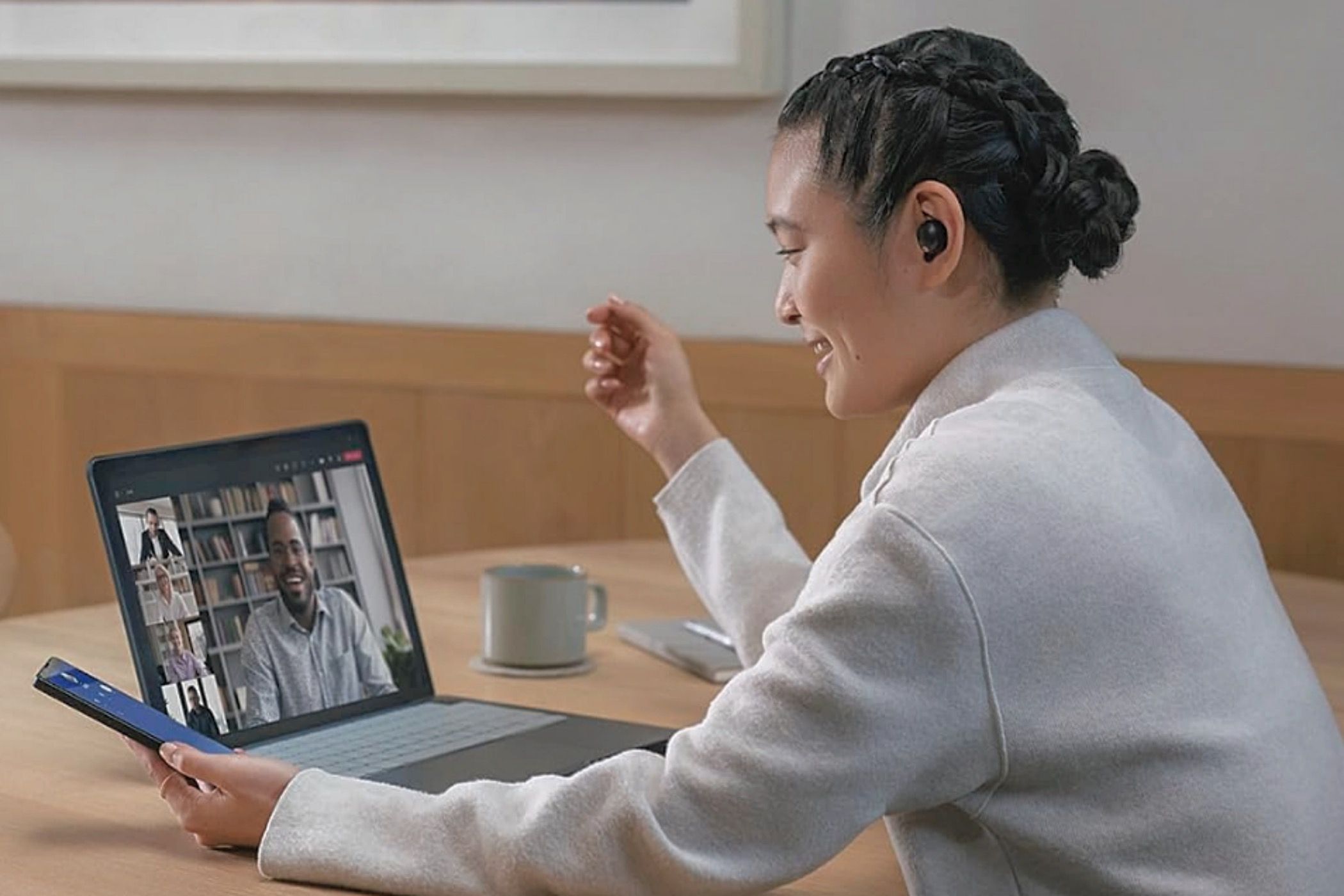 A woman wearing Sony WF-1000XM5 earbuds while chatting on her laptop.