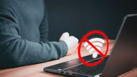 No Wi-Fi Connection icon above laptop with person's arm on table
