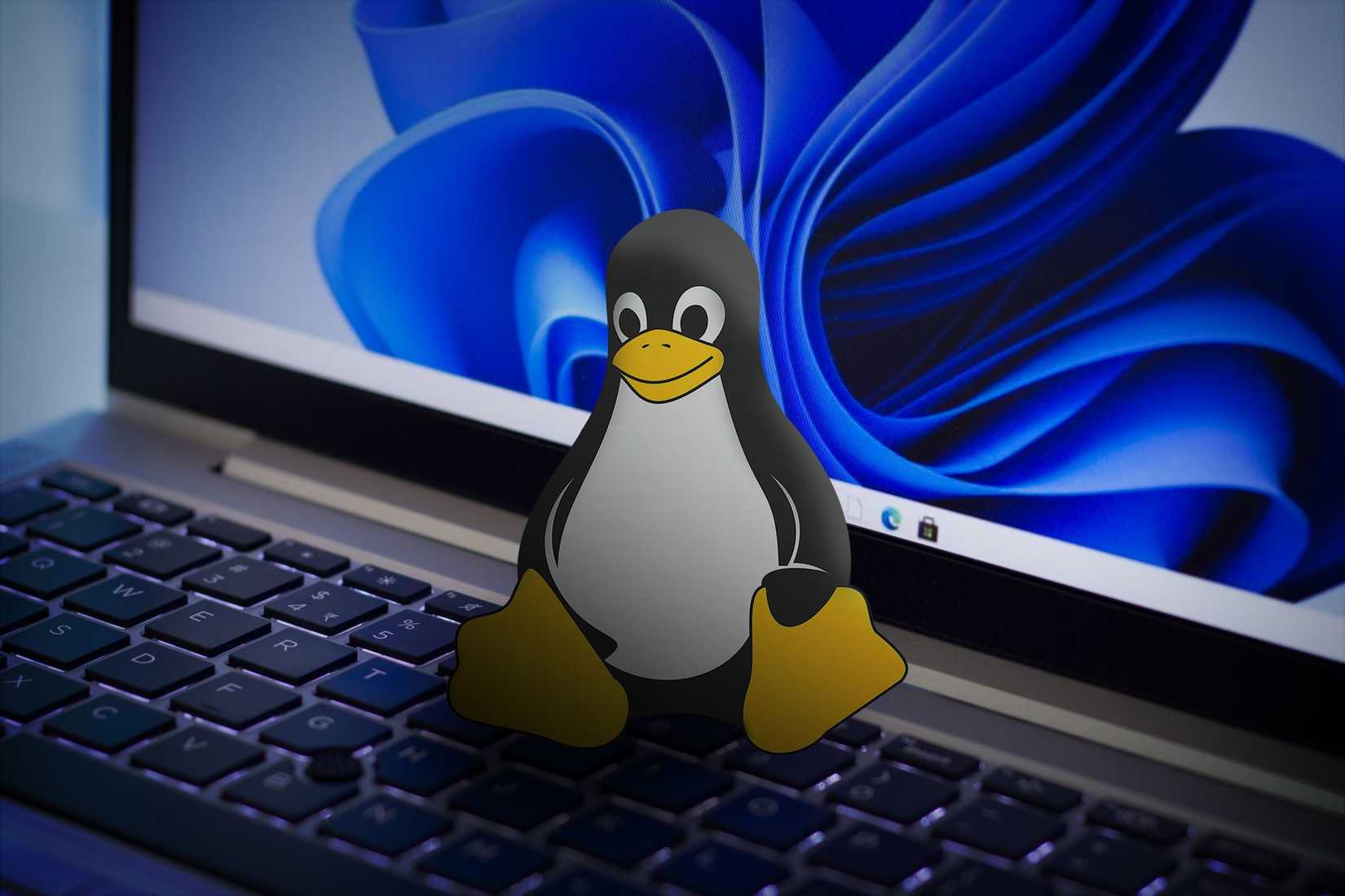 Pictogramă Linux pe o tastatură de laptop cu un fundal Windows 11 pe ecran.