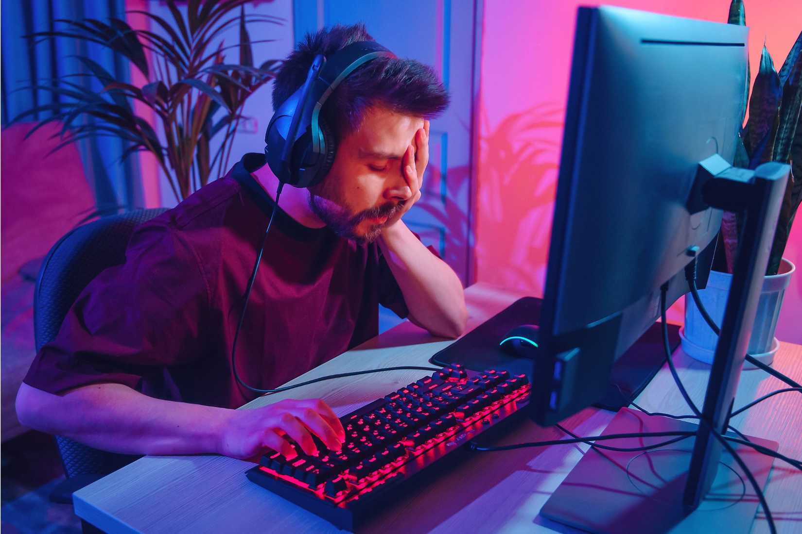 Jucător de PC dezamăgit cu mâna peste față în fața unui computer