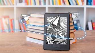 A Kindle leaning against a stack of books with an illustration related to sending around it.