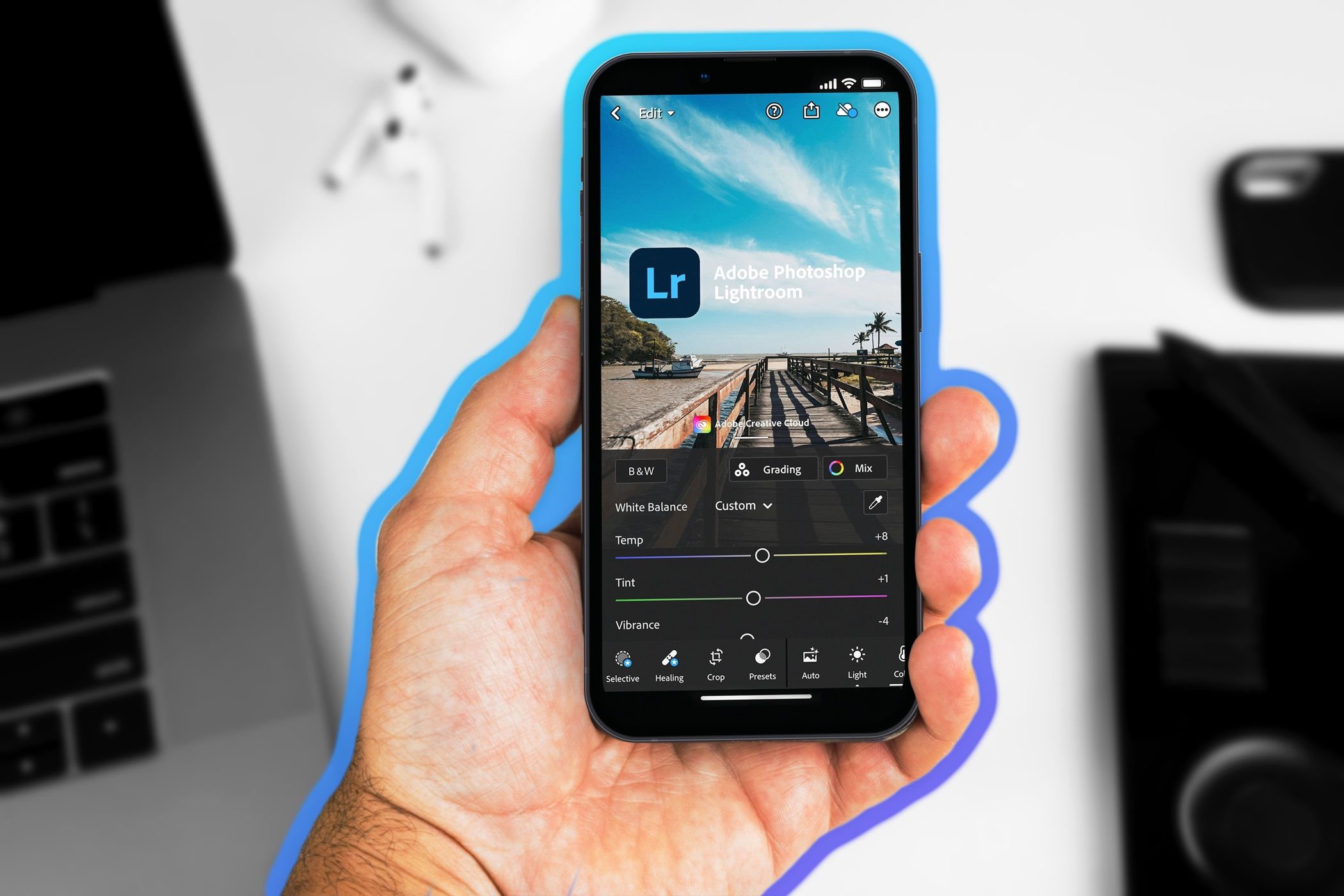 Male hand holding a smartphone with Adobe Photoshop Lightroom app on the screen