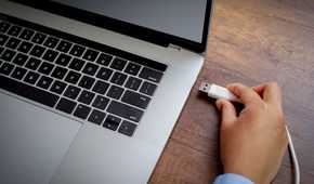 person plugging usb a cable into laptop port