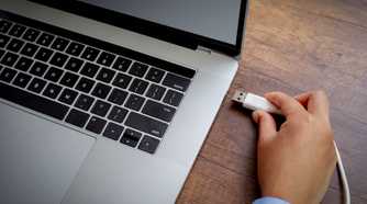 person plugging usb a cable into laptop port