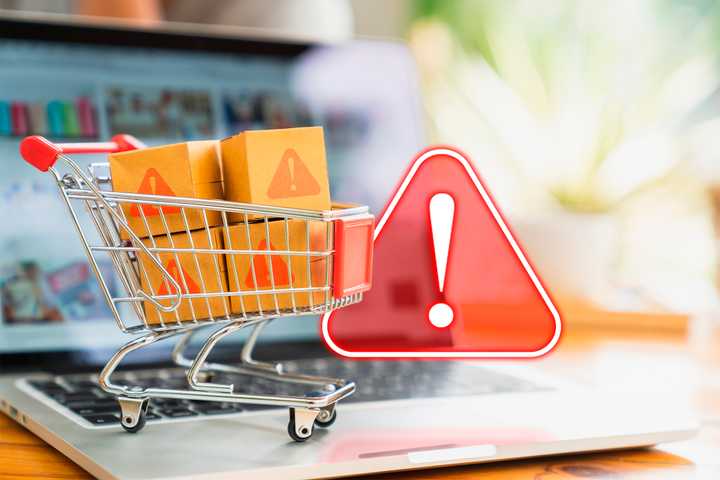A laptop with a shopping cart indicating online shopping and a warning sign.