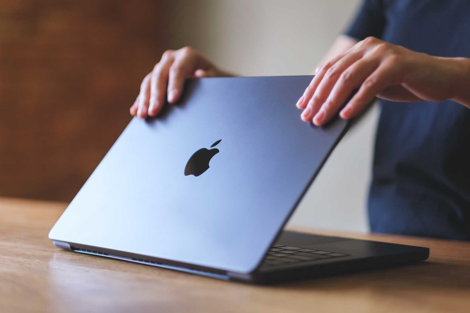 Un hombre cerrando la tapa de un MacBook Air