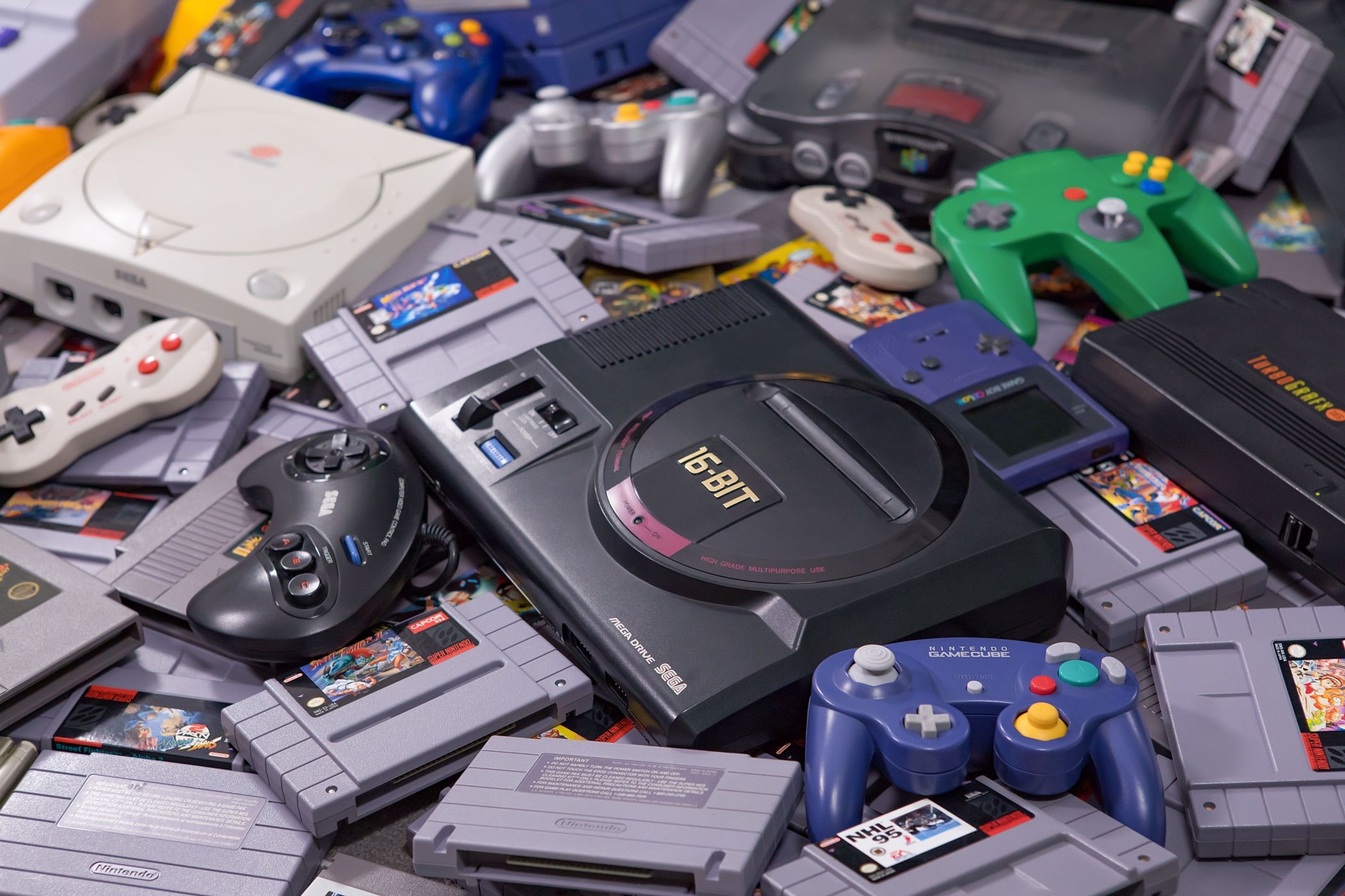 a pile of retro console controllers and cartridges