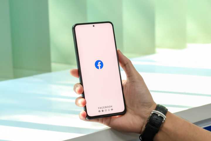 a smartphone with the facebook app held in someone's hand
