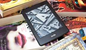 a kindle ereader on a pile of physical books
