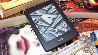 a kindle ereader on a pile of physical books