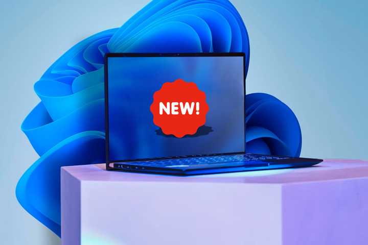 A laptop with NEW sticker on the screen and the Windows 11 wallpaper in the background