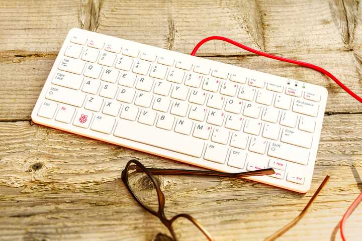 raspberry pi 400 on wooden background with cable