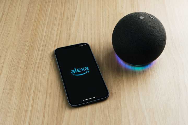 the alexa app on a smartphone on a table next to an echo speaker