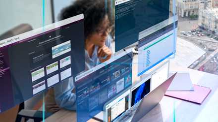 A woman at an office desk using her laptop with multiple virtual desktops.
