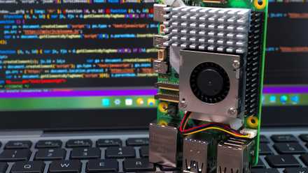 raspberry pi 5 standing on laptop keyboard with code on screen background