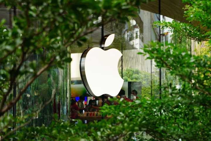 Apple Logo on building set against trees.
