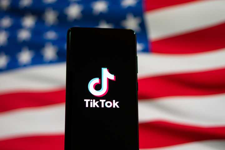 The TikTok logo on a phone in front of the United States flag