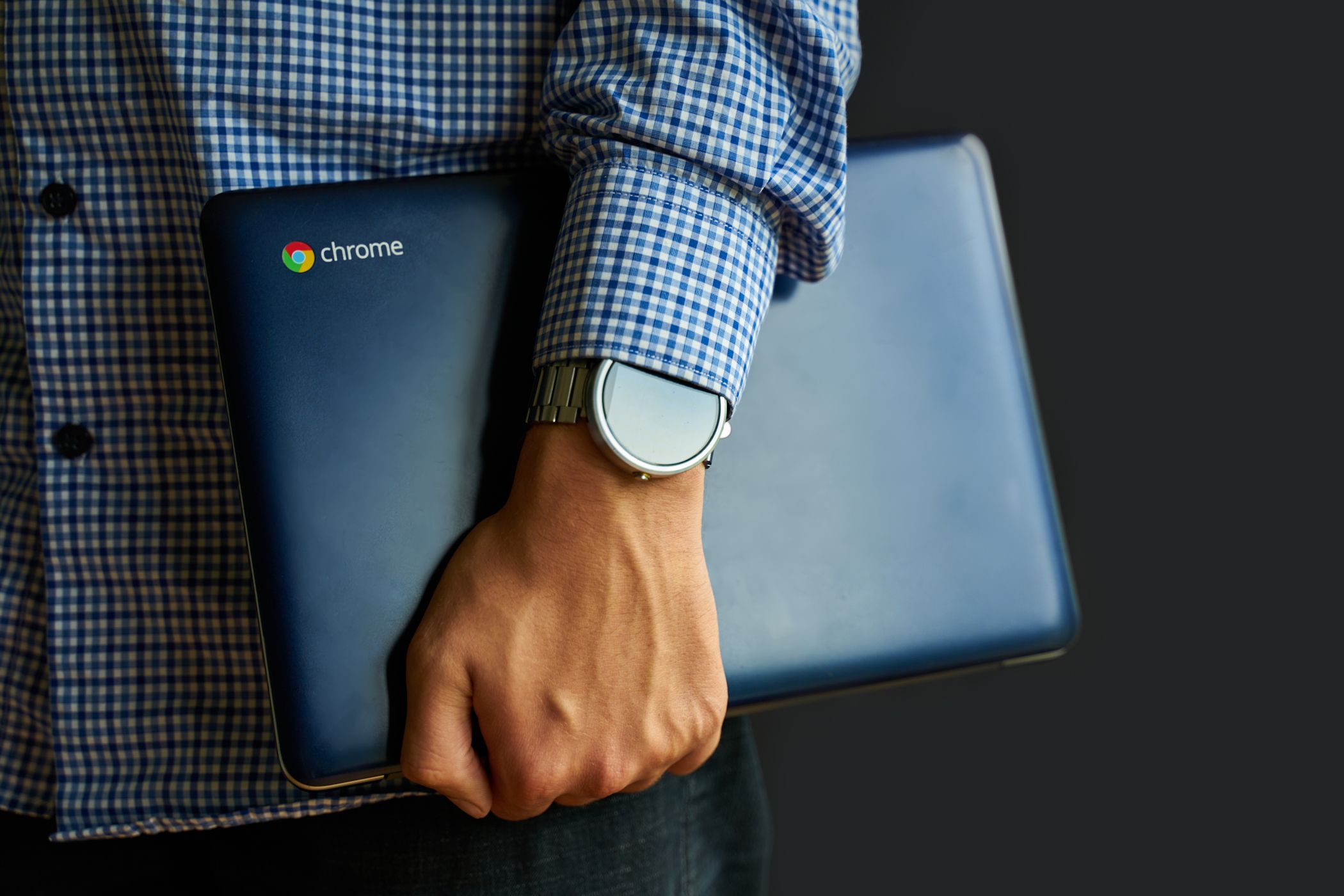 man holding chromebook under arm.