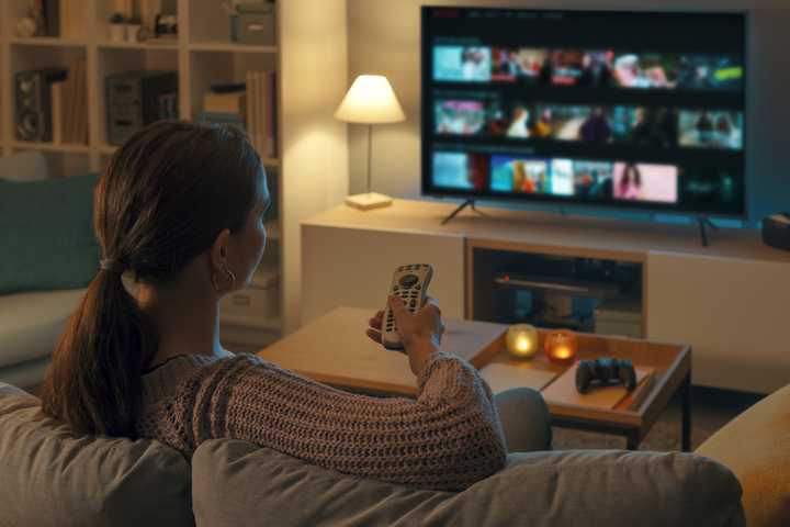 woman using smart tv remote on sofa.