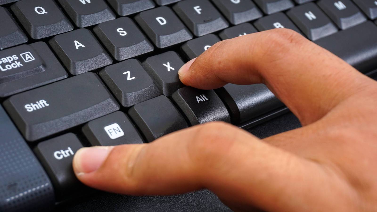 Fingers pressing keys on a PC keyboard