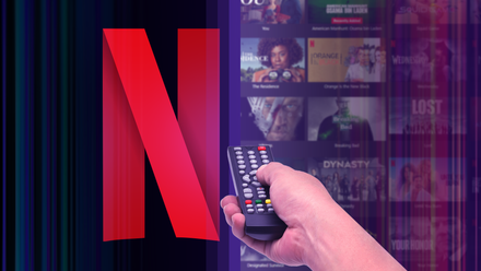 A hand holding a remote control pointed at the Netflix logo, with several shows blurred in the background