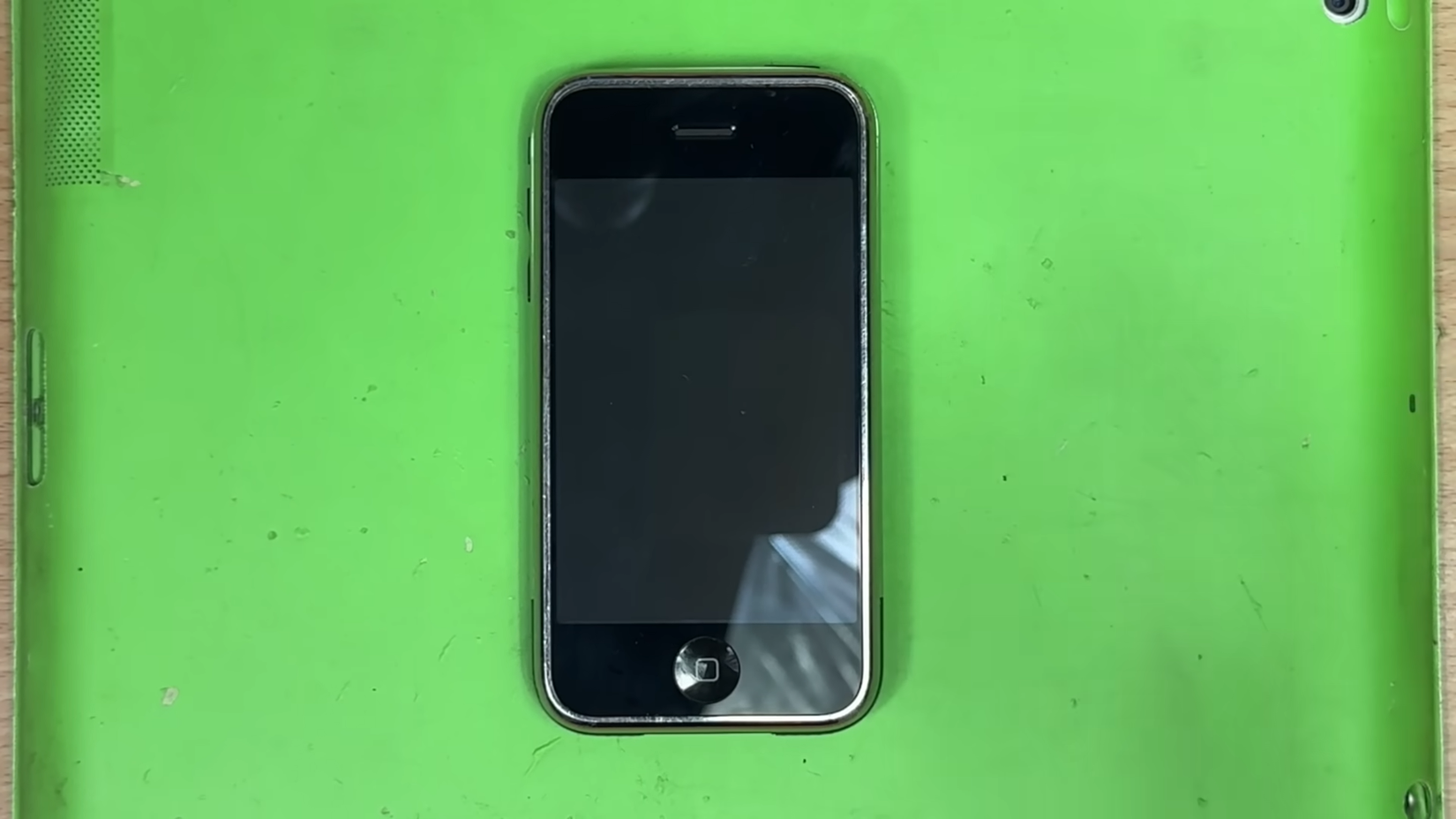 A first-generation iPhone on a lime-green background.