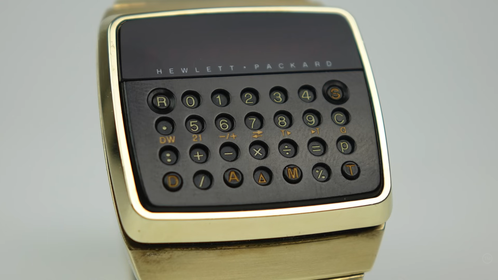 A gold Hewlett-Packard calculator watch with a black keypad and gold accents.