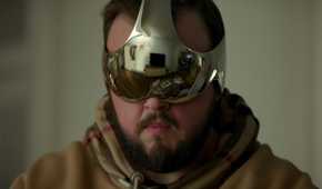 A man in a hoodie wears a reflective metallic visor showing a living room and another person, from Netflix’s 3 Body Problem