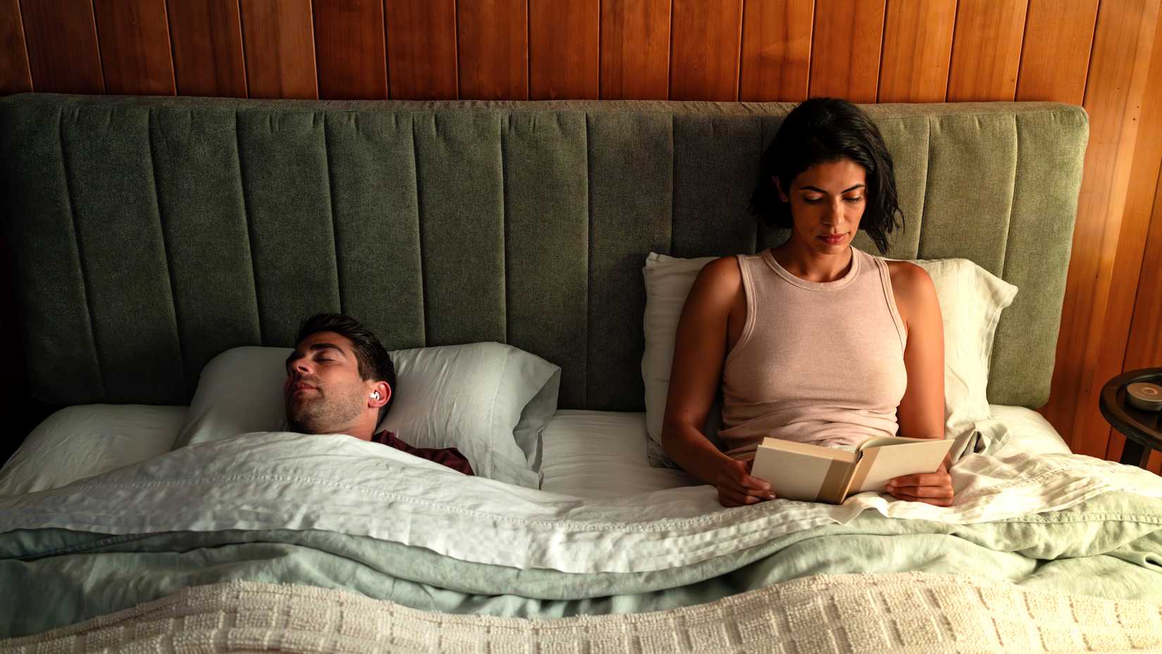 ozlo sleepbuds woman awake while man sleeps in bed.