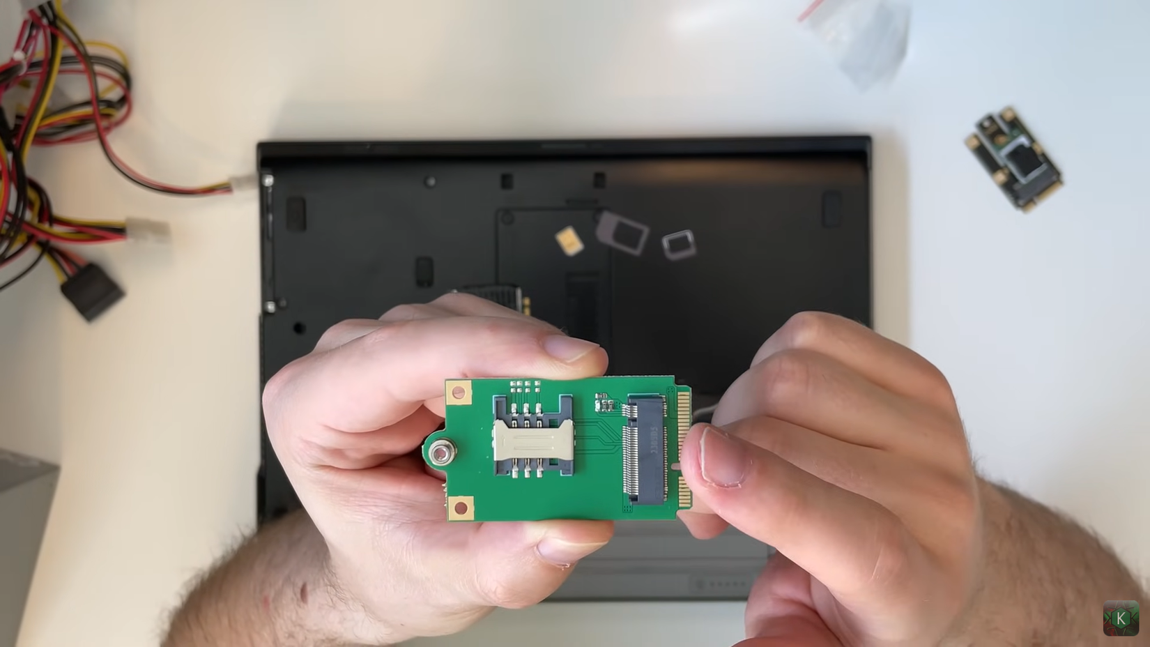Hands holding a small circuit board with a SIM card slot.