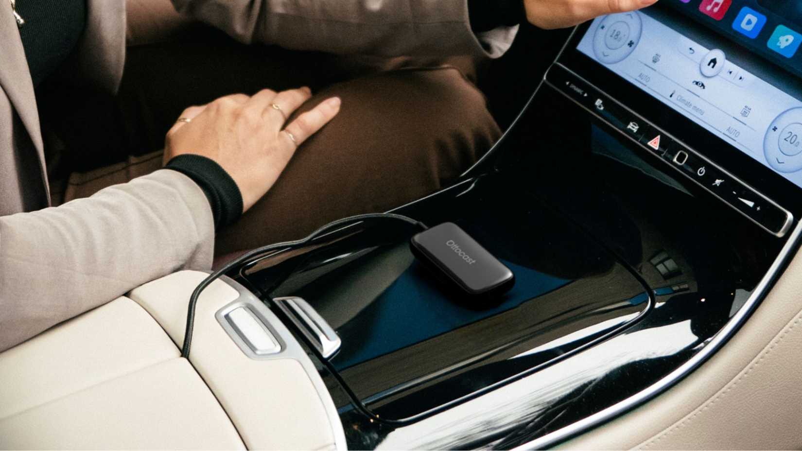 An Ottocast Play2Video Ultra streaming box on the center console of a car.