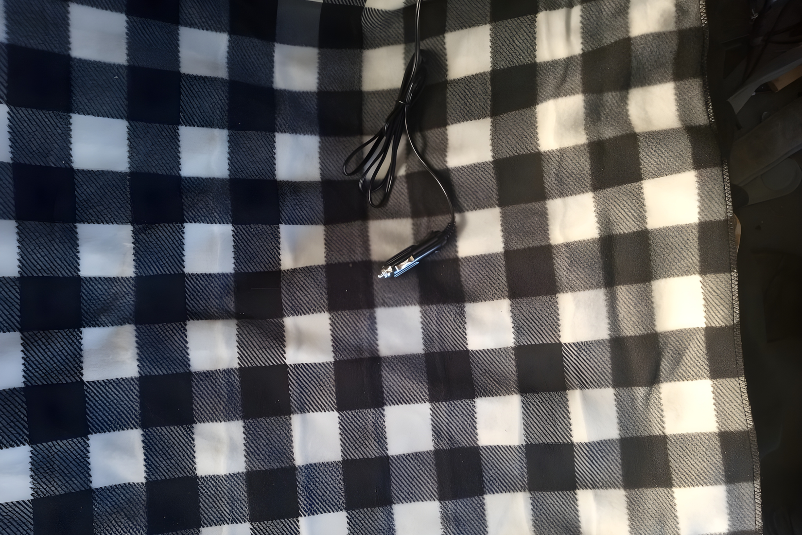 A black and white checkered heated blanket its 12 volts plug on it.